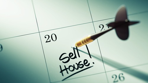 Dart on calendar with writing 'sell house!'